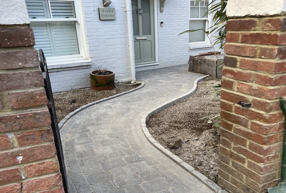 Curved block paving driveway installation leading to a front entrance, showcasing professional patio and driveway landscaping services with clean edging and a modern finish.