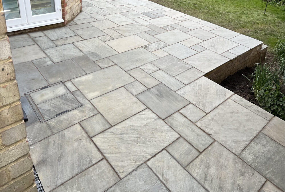 Modern garden patio paving with natural stone effect slabs and raised edge